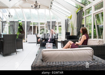 Un rilassato imprenditore professional office manager si siede in una poltrona in un country house hotel in un business suit Foto Stock