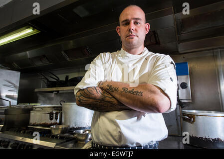 Un professionista significa ^ moody cercando chef sta nella sua cucina, guardando infastiditi con un sacco di apparecchiature di cottura in background Foto Stock