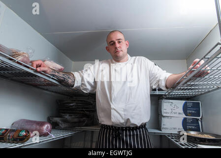 Un professionista significa ^ moody cercando chef sta nella sua cucina, guardando infastiditi con un sacco di apparecchiature di cottura in background Foto Stock