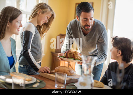 Adulti e bambini si sono riuniti intorno ad un tavolo per un pasto. Foto Stock