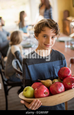 Un ragazzo carring un vassoio in legno di mele. Foto Stock
