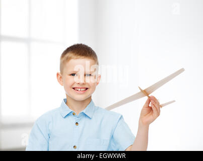 Sorridente ragazzino tenendo un legno modello di aeroplano Foto Stock