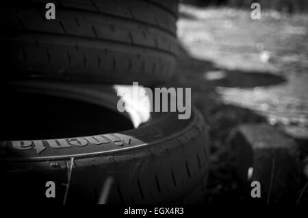 Close up di luce che cade sul mucchio di dumping illegale di pneumatici per auto, UK campagna Foto Stock