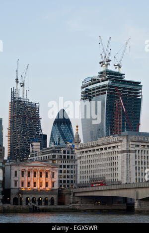 La Swiss Re Insurance edificio, noto anche come "il Gherkin', sorge tra i siti di costruzione dell'edificio Leadenhall, a sinistra e a 20 Fenchurch Street, o il 'Walkie-Talkie edificio", a destra come visto da attraverso il fiume Thames, London, England. Foto Stock