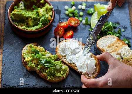 Crostini con diffusione di avocado, formaggio di capra e aglio nero Foto Stock