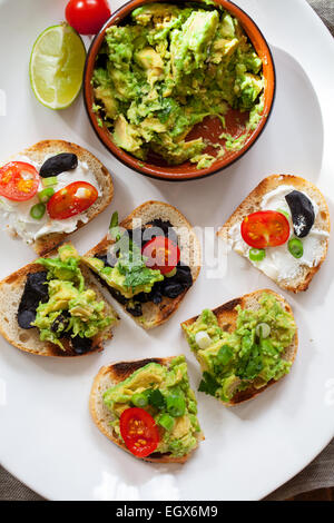 Crostini con diffusione di avocado, formaggio di capra e aglio nero Foto Stock