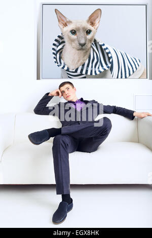 Bello imprenditore pensa, seduto sul divano nel suo ufficio Foto Stock