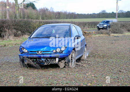 Vettura incidentata attraverso Hedge in campo agricolo. Foto Stock