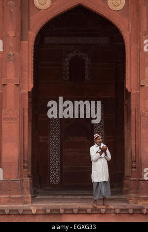 Uomo musulmano in piedi sotto un arco a sesto acuto in Fatehpur Sikri, Uttar Pradesh, India Foto Stock