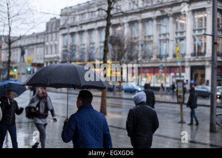 Persone con ombrelloni su Dublino è O'Connell street sotto la pioggia di domenica Foto Stock