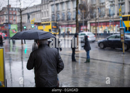 Uomo con ombrello in Dublino è O'Connell street sotto la pioggia di domenica Foto Stock