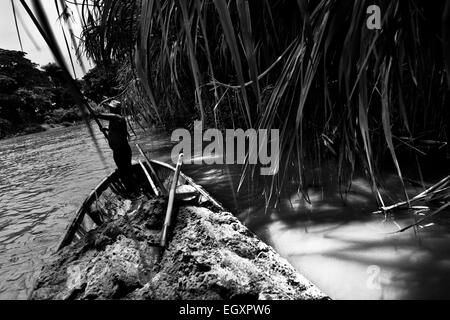 Un colombiano sabbia miner, utilizzando una chiatta pole, naviga la sua barca caricata con sabbia estratta nel fiume la Vieja in Cartago, Colombia. Foto Stock