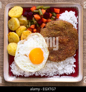 Tradizionale piatto boliviano chiamato Silpancho, che è il nome dell'impanati, piatto tondo di carne di manzo con verdure riso Foto Stock