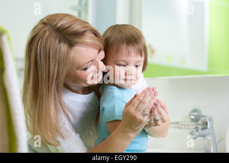 Kid boy lavarsi le mani con sapone in bagno Foto Stock