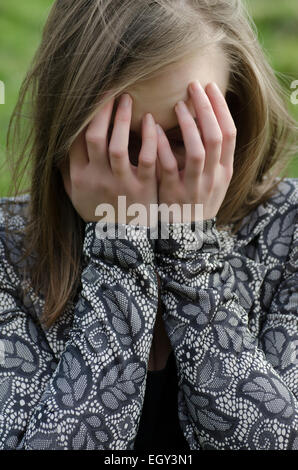 Giovane donna testa in mani piangendo all'aperto Foto Stock