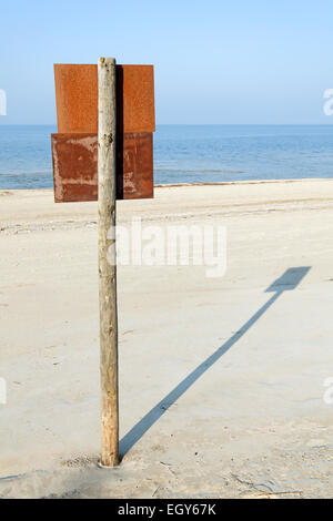 Scheda arrugginito segno sul palo di legno su una spiaggia. Foto Stock