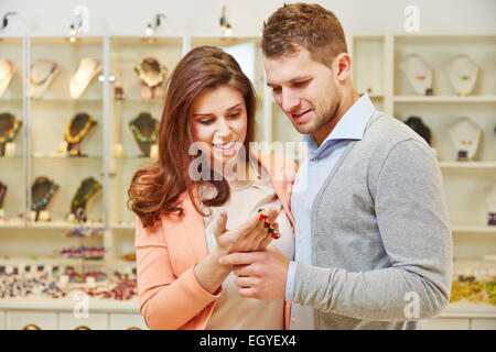 Coppia sorridente guardando il braccialetto e altri gioielli al gioielliere Foto Stock