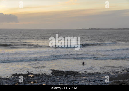 Sera Surfer sulla spiaggia Ogmore nel Galles del Sud Foto Stock