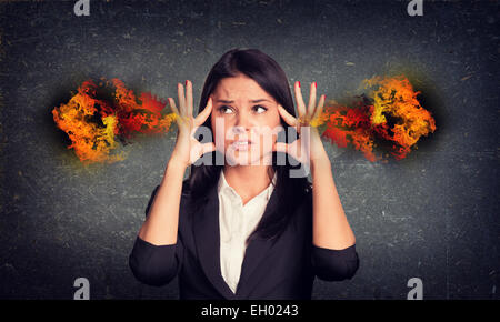 Vivendo la donna con il fuoco dalle orecchie. Calcestruzzo parete grigia come sfondo Foto Stock