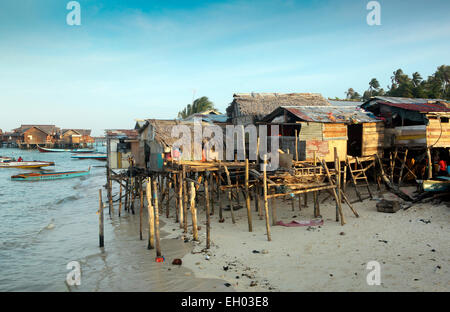 Sgangherato alloggiamento locale su palafitte oltre oceano con scuba diving resorts in background a Mabul Island, Borneo Foto Stock