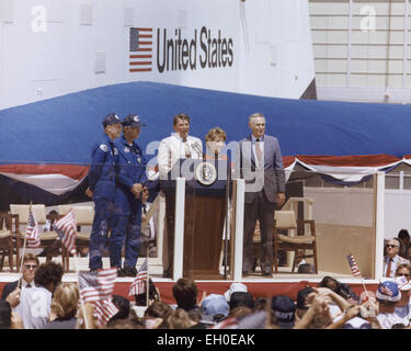 Questa giornata nella storia - 6 Feb 1911: è stata la nascita di Ronald Reagan: uomo politico americano, il presidente degli Stati Uniti, 1981-1989. Avviate "guerre stellari" difese strategiche e la stazione spaziale Freedom. Il Presidente Ronald Reagan parla a una folla di oltre 45.000 persone alla NASA Dryden Flight Research Center dopo lo sbarco di STS-4 il 4 luglio 1982. A destra del Presidente sono la sig.ra Nancy Reagan e amministratore della NASA James M. Beggs. A sinistra sono STS-4 Columbia astronauti Thomas K. Mattingly e Henry W. Hartsfield, Jr. prototipo Space Shuttle Enterprise è in background. Foto Stock