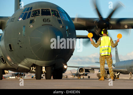 Un Royal Australian Air force manutentore di aeromobili esegue il marshalling di un RAAF C-130J Super Hercules in posizione dopo una missione di addestramento durante la bandiera rossa 15-1 presso la Base Aerea Militare di Nellis Nev., Gennaio 27, 2015. La simulazione di battaglia di formazione fornita da Red Flag nel cielo sopra il Nevada Test e campo di addestramento ha dato risultati che aumentano la capacità di combattimento degli Stati Uniti e le forze aeree alleate per l'per il futuro del mondo reale di situazioni di combattimento. Foto Stock