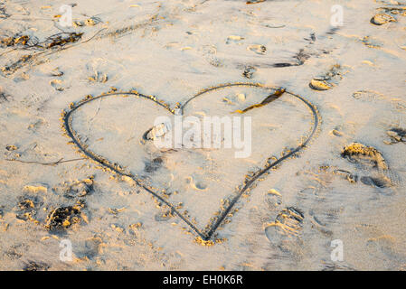 A forma di cuore scolpito nella sabbia sulla spiaggia. Foto Stock