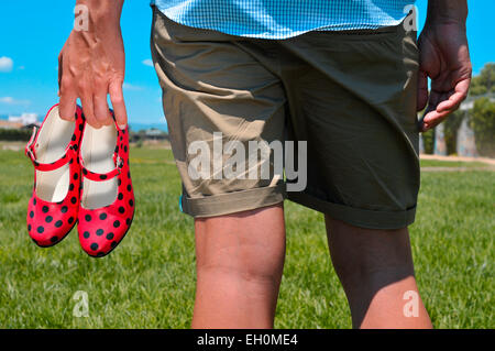 Dettaglio di un giovane con una coppia di tipico colore rosso e nero dot-modellato scarpe di flamenco in mano Foto Stock