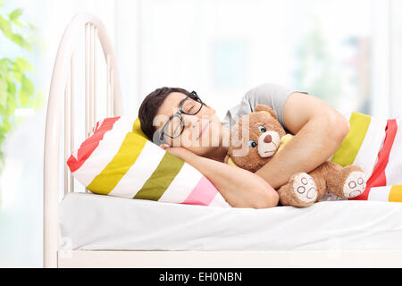 Infantile giovane uomo dorme con un orsacchiotto di peluche a casa Foto Stock