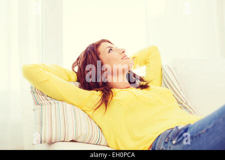 Sorridente giovane donna sdraiata sul divano di casa Foto Stock