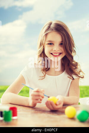 Sorridente bambina colorare le uova per la pasqua Foto Stock