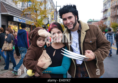 Il padre e la madre vestita come Wolverine tenendo il loro figlio vestita come una scimmia durante l'Halloween 2013 a Newark, New Jersey. Foto Stock