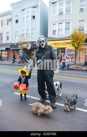 Padre holding figlie mano sia in costumi durante il periodo di Halloween 2013 nelle strade di Newark, New Jersey. Foto Stock