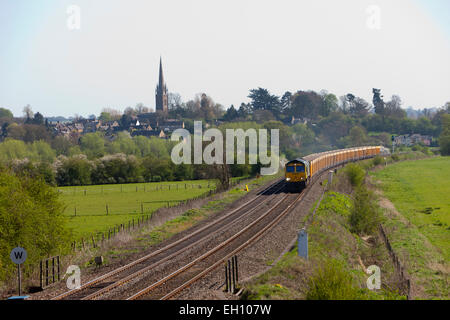 Un treno merci si avvicina passato un piccolo villaggio nella contea di Oxford, Inghilterra Foto Stock