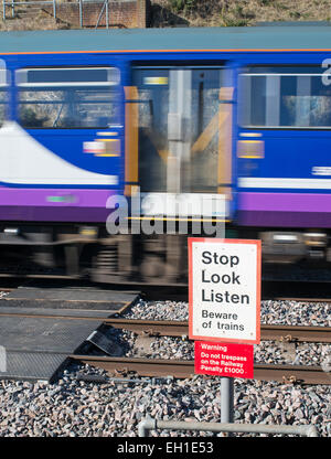 Velocità del treno sfocata passa ungated livello pedonale attraversamento su ferrovia, Durham costa North East England Regno Unito Foto Stock