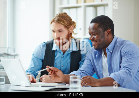 Due uomini a discutere di presentazione del notebook in ufficio Foto Stock