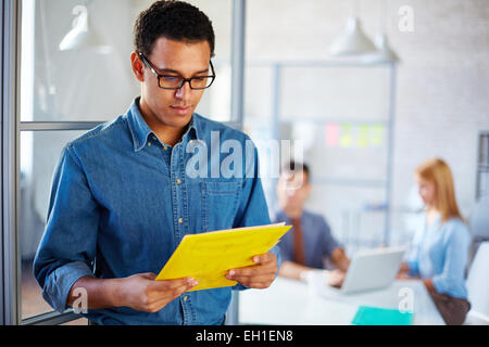 Giovane imprenditore carta lettura in ambiente di lavoro Foto Stock