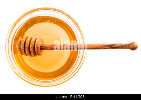 Il miele in recipiente di vetro con immersione in legno stick, isolato su bianco. Foto Stock