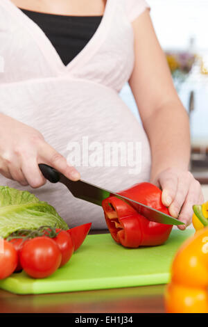 Donna incinta sminuzzare verdure fresche Foto Stock