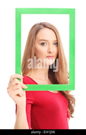 Bella donna in posa e tenendo un'immagine verde telaio nella parte anteriore del suo viso isolati su sfondo bianco Foto Stock