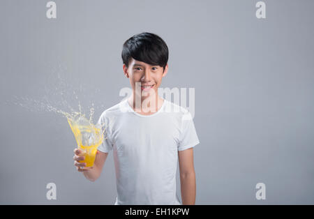 Giovane uomo con spruzzi di succo d'arancia Foto Stock