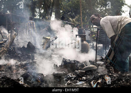 Sivasagar, Assam, India. Mar 5, 2015. Un uomo guarda per i suoi beni dopo la sua casa bruciata alla zona Khatapathar Sivasagar nel distretto di nord-est Assam il 5 marzo 2015. Almeno 20 case sono state bruciate dopo l incendio scoppia a causa di una bombola di gas blast da una casa. 5 persone di cui 1 donna si è infortunato per il fatto che la bombola di gas blast. Credito: Luit Chaliha/ZUMA filo/ZUMAPRESS.com/Alamy Live News Foto Stock