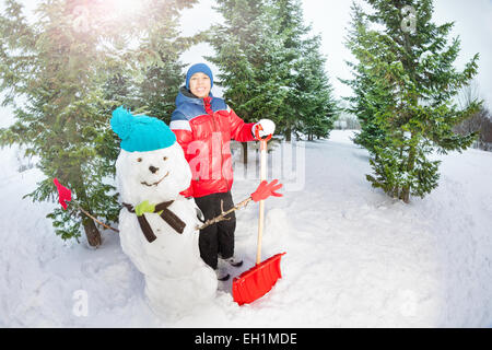 Arabian ragazzo con la pala in piedi vicino pupazzo di neve Foto Stock