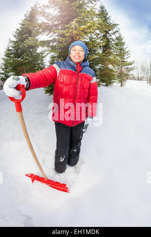 Arabian ragazzo con pala in inverno durante il giorno Foto Stock