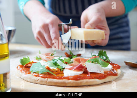 Aggiunta di ingredienti per fatti in casa la pizza Foto Stock