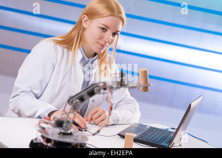 Schoolgirl regola il braccio di robot modello, ragazza in un laboratorio di robotica Foto Stock