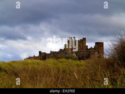 Il castello di Bamburgh stagliano contro un cielo minaccioso presi da le dune della spiaggia sulla costa di Northumberland England Regno Unito Foto Stock