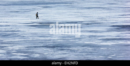 Un pescatore solitario è sul ghiaccio del fiume di inverno Foto Stock