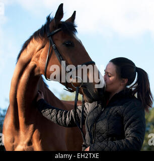 Una giovane donna baciare un cavallo sul suo naso Foto Stock