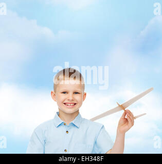 Sorridente ragazzino tenendo un legno modello di aeroplano Foto Stock